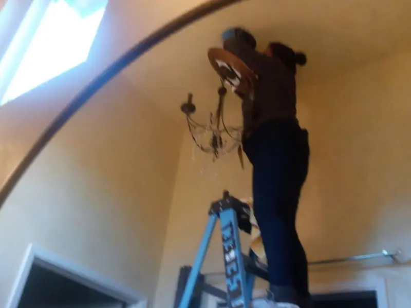 Electrician installing a chandelier in a Tolono residence